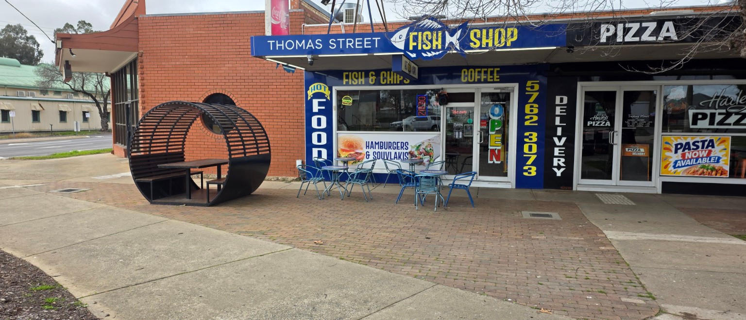 Thomas Street Fish Shop storefront in Benalla, with its blue and yellow sign, entrance and outdoor seating